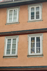 Four windows on a building facade with a decorative element inside one. Architectural detail, European architecture, outdoor scene, textured wall.
