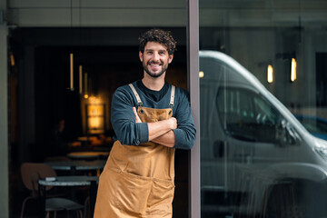 Handsome waiter waiting for customers while leaning on the coffee shop door