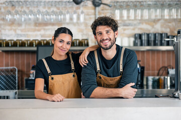 Two younger waiters looking at camera in a pastry shop.