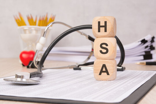 Wooden blocks with "HSA" letters representing Health Savings Account with medical accessories