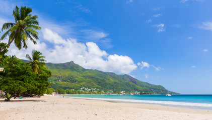 A tranquil tropical beach with lush green mountains in the background,