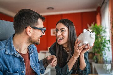 Adult caucasian couple save money coins in the piggy bank at home