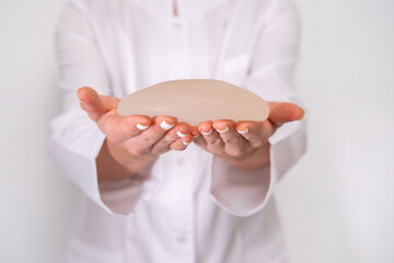 doctor holding breast enlargement implant in hands, plastic surgery concept, beauty enhancement,...