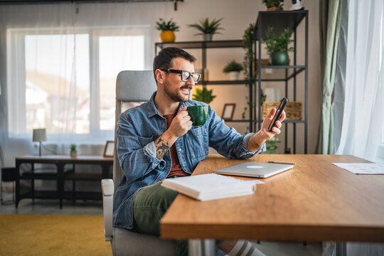relaxed man drink coffee and use mobile phone from home office