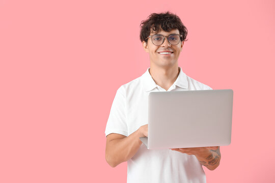 Male programmer working with laptop on pink background
