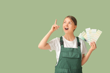 Female decorator with color palettes and raised index finger on green background