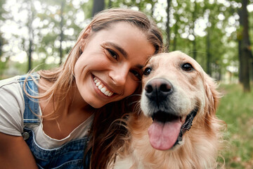 A Joyful Interaction Between a Young Woman and Her Golden Retriever in Nature Outdoors