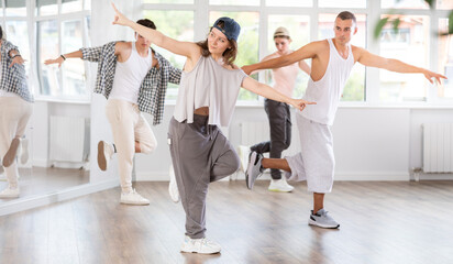 Obraz premium Dynamic young woman training hip hop kick steps in dancehall during workout session