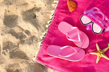 Towel with flip-flops and snorkeling mask on sand