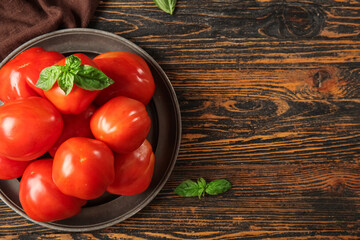 Plate with fresh ripe tomatoes and basil on wooden background