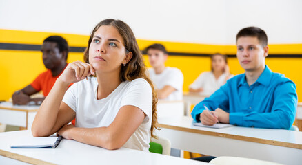 Young woman sitting at desk in classroom of school for taxi drivers.
