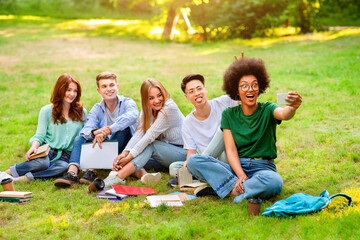 Fototapeta premium Happy Multicultural College Students Having Fun While Taking Group Selfie Outdoors, Sitting On Grass In Park. Having Break In Study, Copy Space