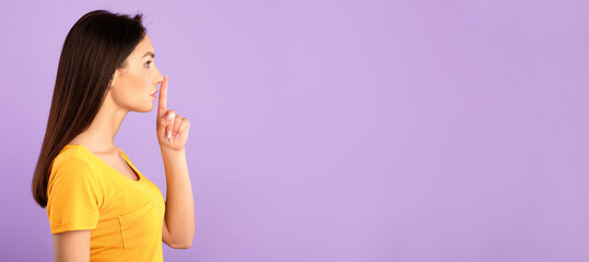 Shh, Keep Silence, Be Quiet Concept. Side view profile portrait of young woman putting finger on...