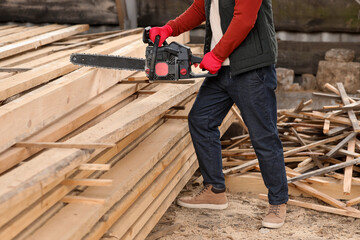 Male carpenter sawing wooden plank at sawmill