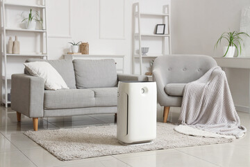 Interior of light living room with air purifier, sofa and armchair