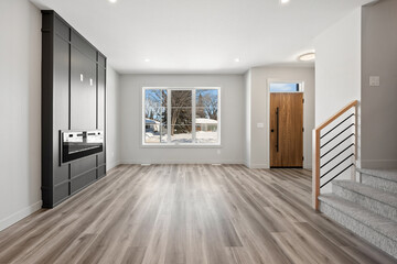 Large, empty living room with a fireplace and a staircase