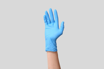 Female hand in medical glove on grey background