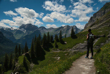 Fototapeta premium Girl hikers on the path of the Oeschinen Lake viewpoint trail, with idyllic mountain scenery. Located in the Bernese Oberland, Switzerland. Photography in spring and looking for adventure. 