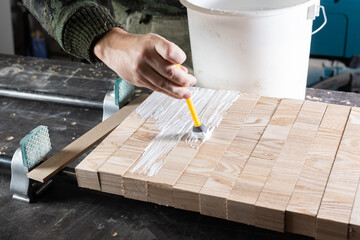 The carpenter applies joiner's glue to the ash bars for gluing