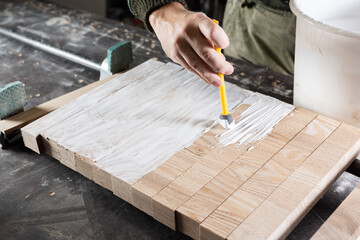 The carpenter puts glue on the ash bars for gluing