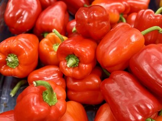 Vibrant red bell peppers are abundant in a market basket, showcasing their freshness and vivid color. Close-up