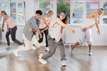 Dynamic young woman training hip hop steps in dancehall during workout session