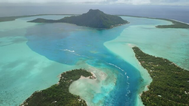Aerial view capturing Bora Bora lush vegetation, crystal clear turquoise water, intricate lagoon channels, creating breathtaking tropical paradise in French Polynesia. Remote wild nature destination