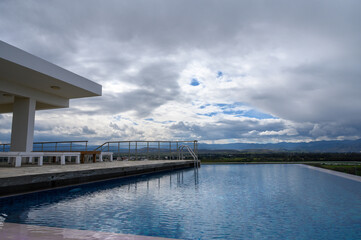 Skyline reflections near a serene pool with scenic mountains in the background under a moody sky