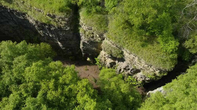 Aerial view of Maltas Canyon, Dagestan, capturing mossy mountains, alpine trees, a mountain river, and dynamic cloud shadows under golden sunlight.