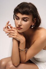 Elegant model poses with minimal accessories in a soft studio setting during a fashion photoshoot