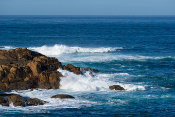 seething long ocean waves with white foam crashing against coastal rocks (seascape)