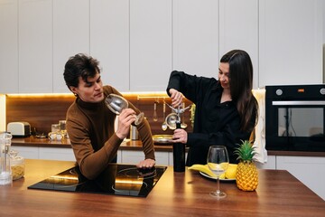 Couple enjoying a playful moment in their modern kitchen while preparing drinks