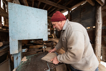 Carpenter Cutting Wood with a Bandsaw in a Rustic Workshop