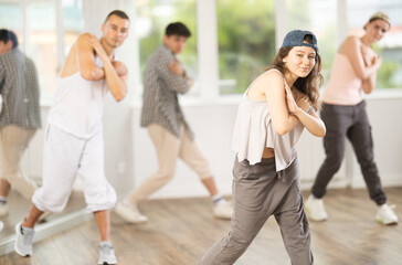 Young girl standing performs basic hip hop movements in front of group of students. Developing...