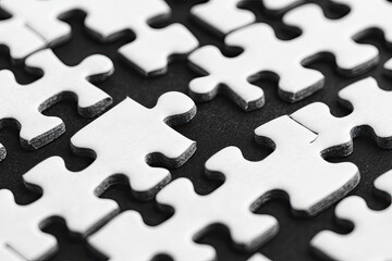 Closeup of White Jigsaw Puzzle Pieces on Black Background Showing Interlocking Sections and Gaps