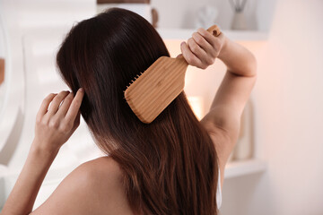 Naklejka premium Woman brushing her beautiful hair at home