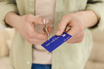 Man cutting his credit card indoors, closeup