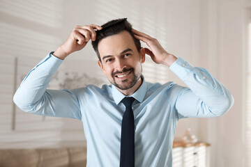 Handsome man combing his hair at home
