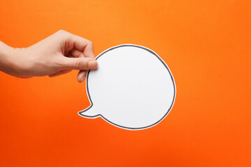 Woman holding blank speech bubble on orange background, closeup. Space for text