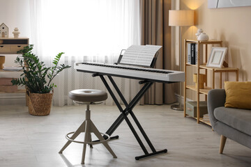 Synthesizer with music sheets and stool indoors