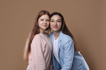 Portrait of beautiful mother with teenage daughter on dark beige background