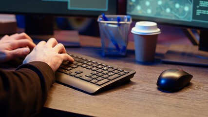 Meticulous hacker typing on computer keyboard, doing data breaches and financial theft in dark...