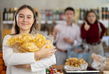 Angry couple adult man and young woman scold teenage daughter with chips in grocery store