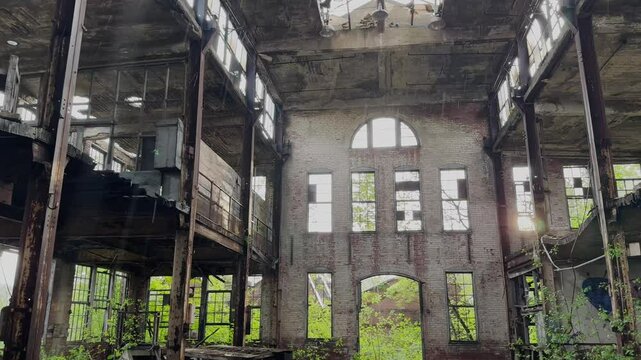 A towering, decayed factory in Youngstown, Ohio. Rusted beams, shattered windows, and crumbling walls frame the sunlight as nature slowly reclaims this forgotten industrial space.