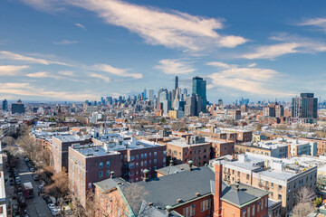 Naklejka premium A breathtaking view of Brooklyn showcasing its diverse architecture, from historic brownstones to contemporary buildings, with the iconic Manhattan skyline rising in the background. The contrast betwe