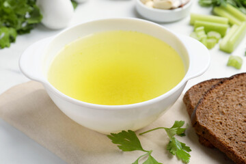 Tasty chicken bouillon in bowl served on white table, closeup