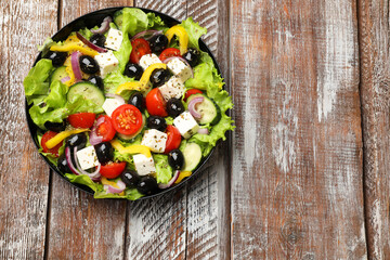 Delicious fresh Greek salad on wooden table, top view. Space for text