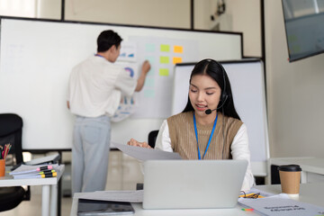 Finance analyst working on a laptop while discussing tax deductions with a colleague in a modern office.