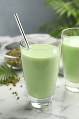 Fresh mung bean juice in glasses and seeds on white marble table, closeup