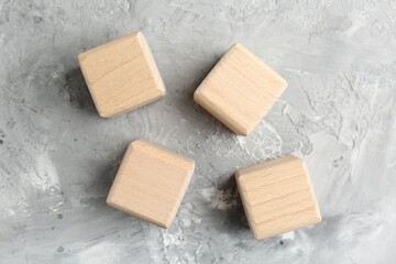 Blank wooden cubes on grey textured table, flat lay